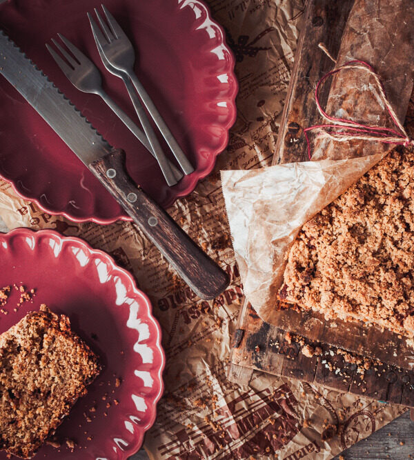 Top view Bananenbrot mit Streuseln, zwei rote Teller mit Kuchengabeln und einem Brotmesser