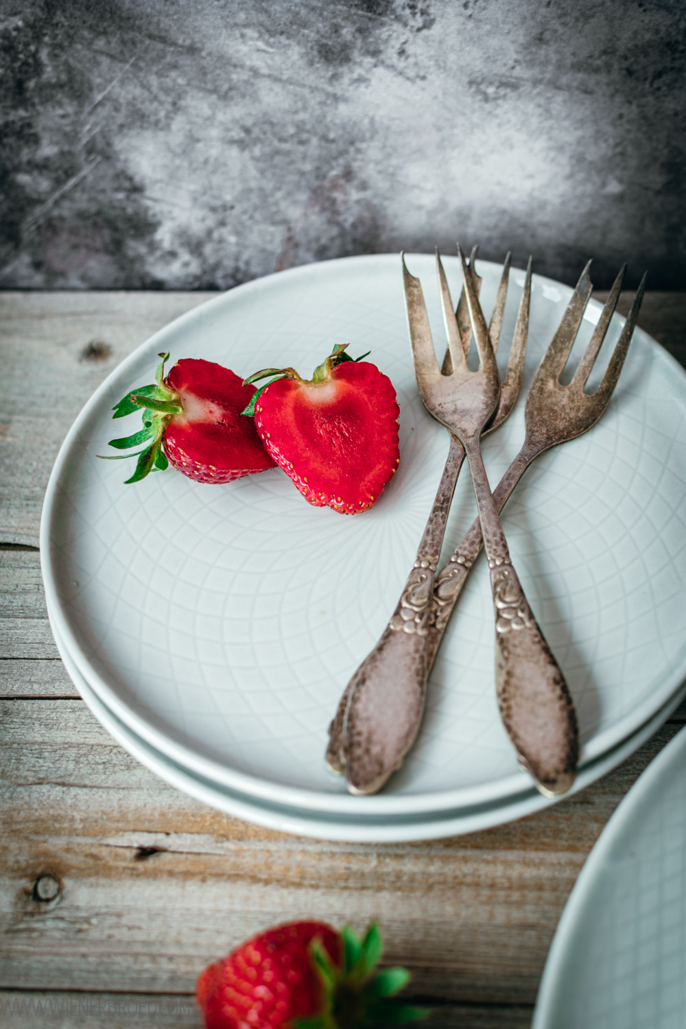 Erdbeeren und Kuchengabeln auf Tellerstapel