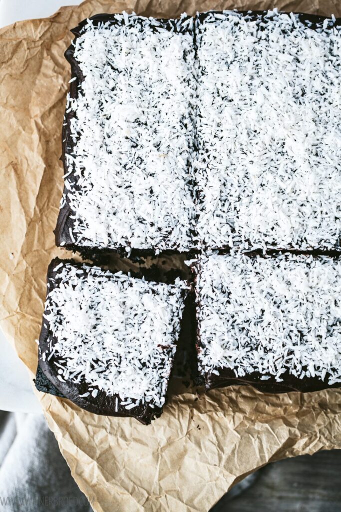 Geschnittener Kuchen mit Kokosraspeln auf Backpapier