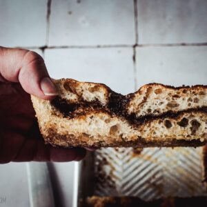 Hand, die ein Stück Focaccia mit Zimt und Zucker hält