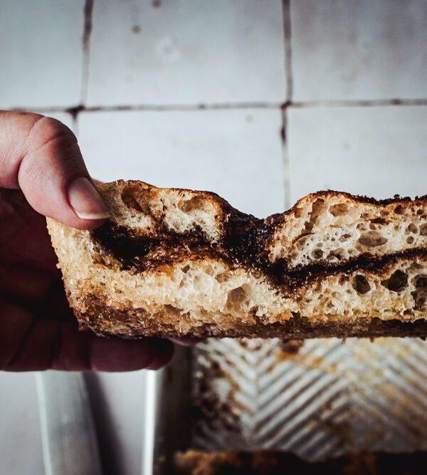 Hand, die ein Stück Focaccia mit Zimt und Zucker hält