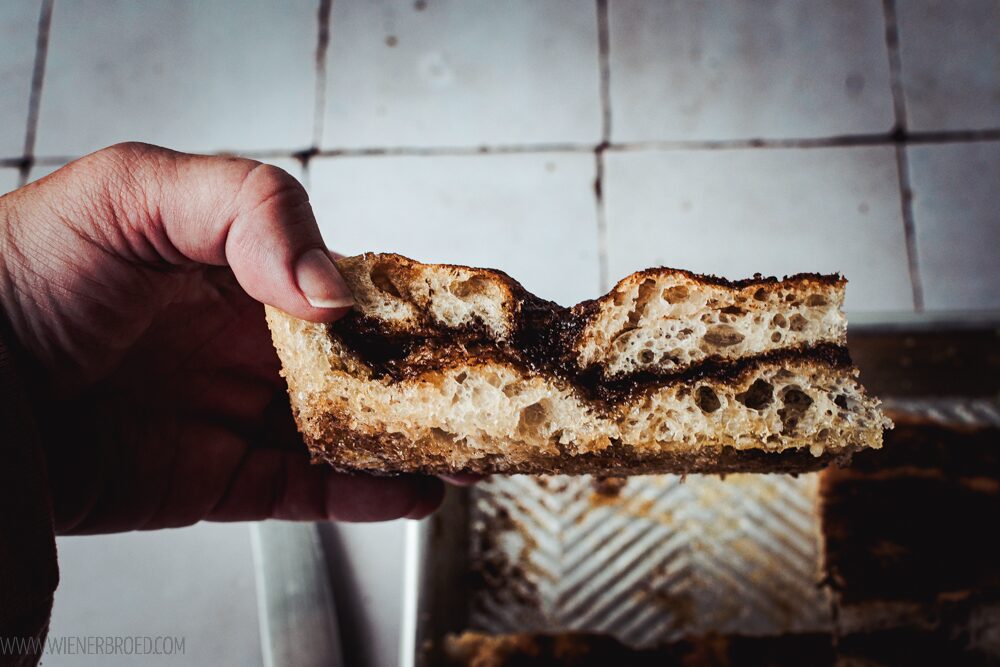 Hand, die ein Stück Focaccia mit Zimt und Zucker hält